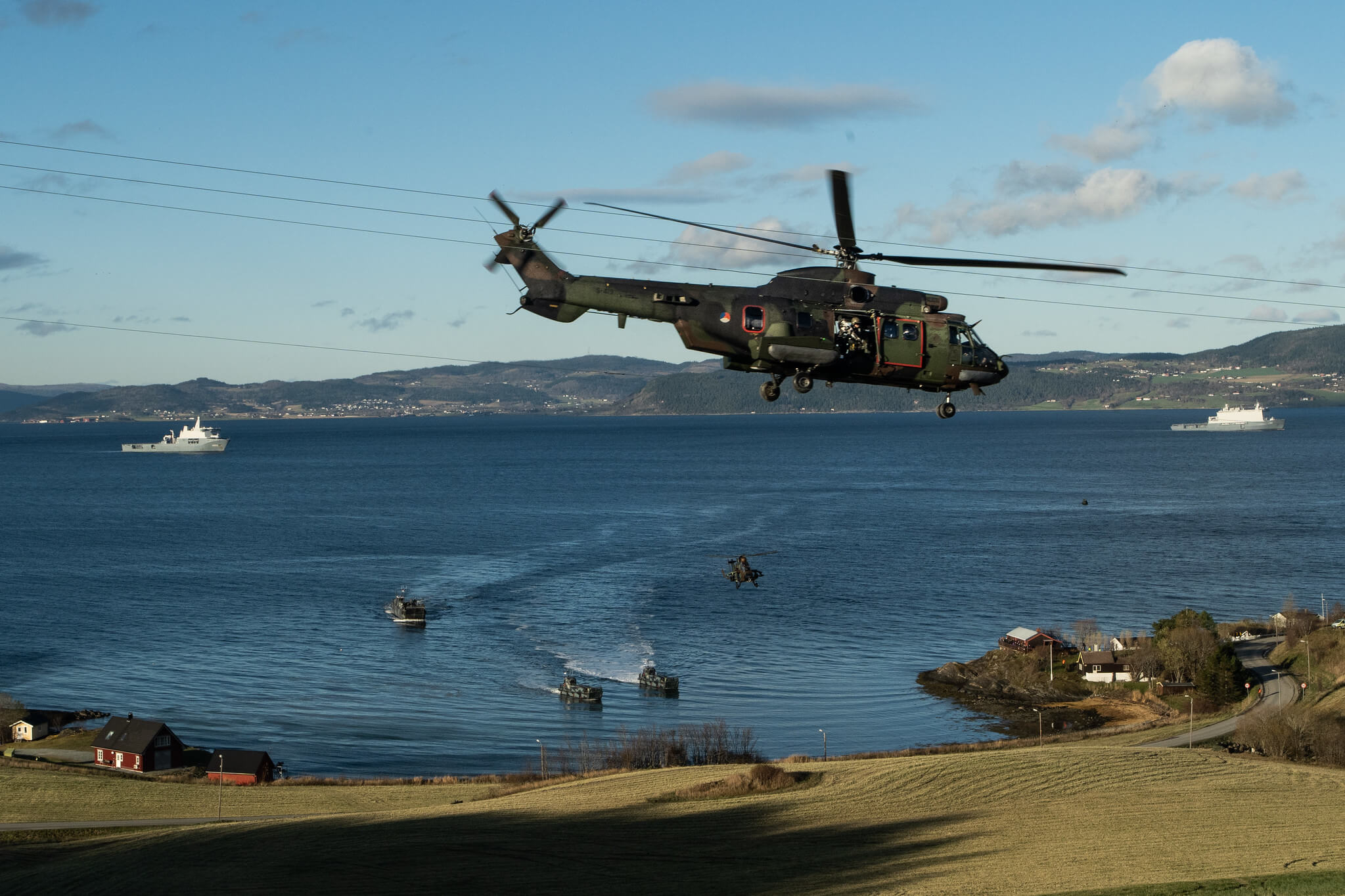 Boxhoorn - A Dutch Cougar helicopter takes off while NATO forces prepare to make an amphibious landing at a media event held during Exercise Trident Juncture 18 in 2018. NATO