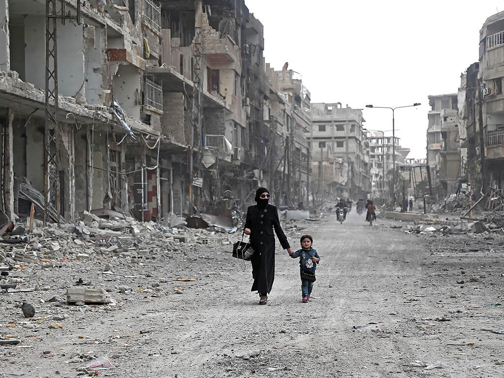 A Syrian woman and child walk down a destroyed street in Arbin, Ghouta region. ©Flickr/Jordi Bernabeu