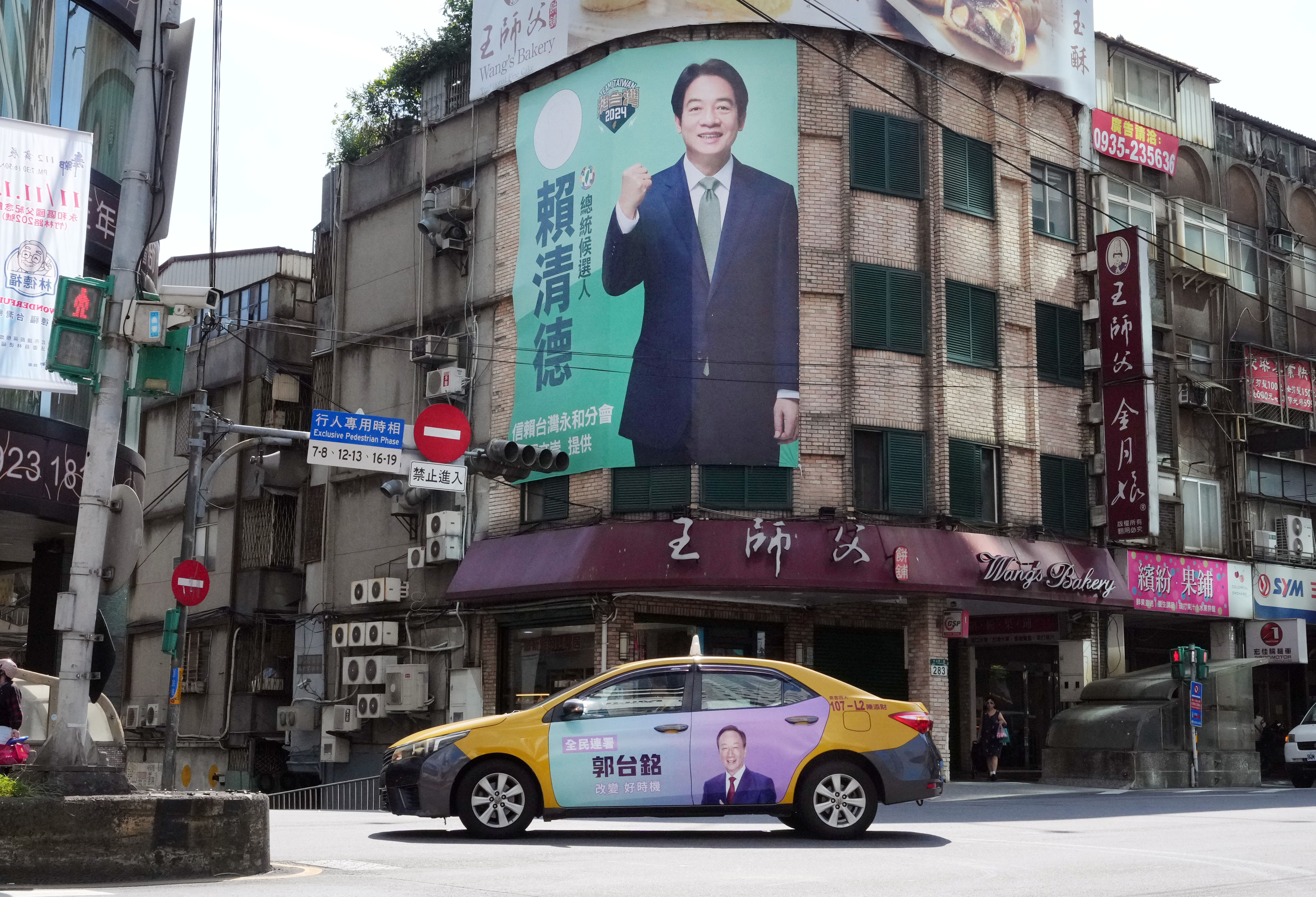 Some advertisements of candidates are seen on a building wall and a taxi prior to Taiwan's presidential election in New Taipei City, Taiwan on 8 November 2023. The Yomiuri Shimbun via Reuters