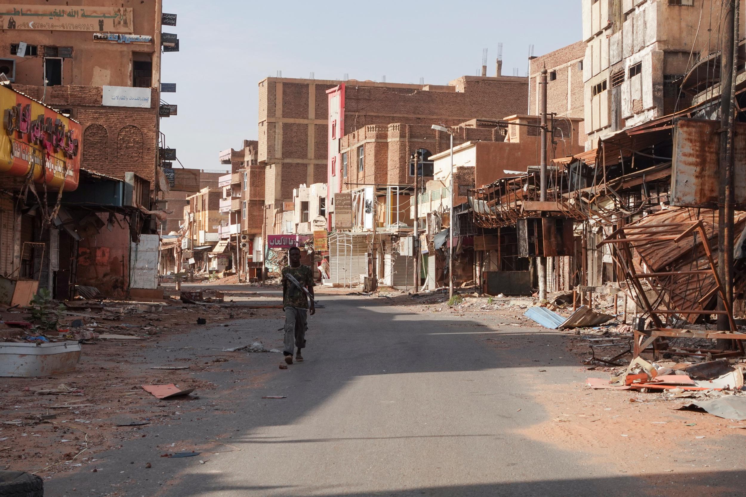 A member of the Sudanese Armed forces walks between damaged buildings in Omdurman, Sudan, 7 April 2024. © El Tayeb Siddig via Reuters