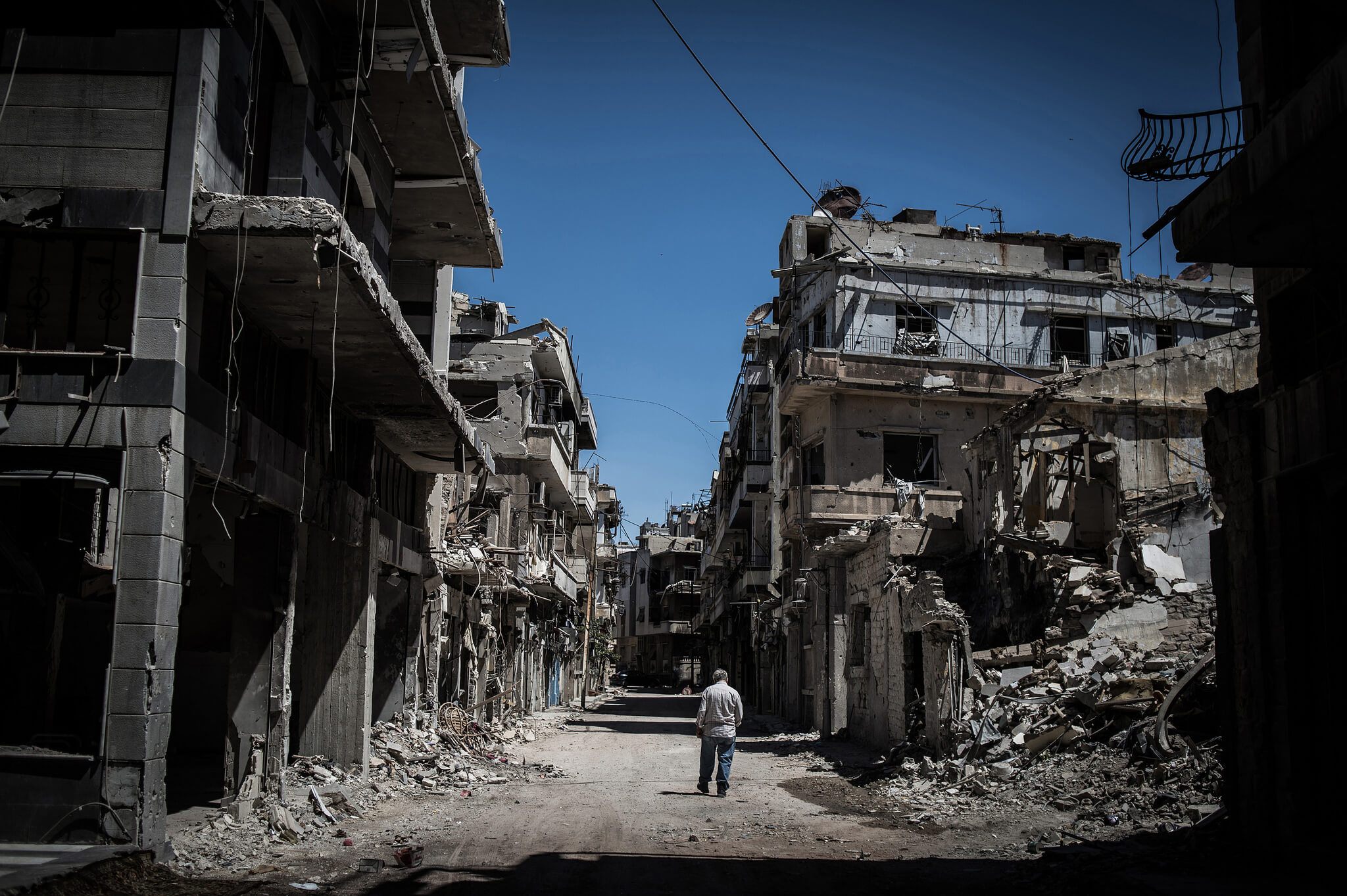 Een Syrische vluchteling loopt in een verwoest Homs.  © Chaoyue Pan / Flickr