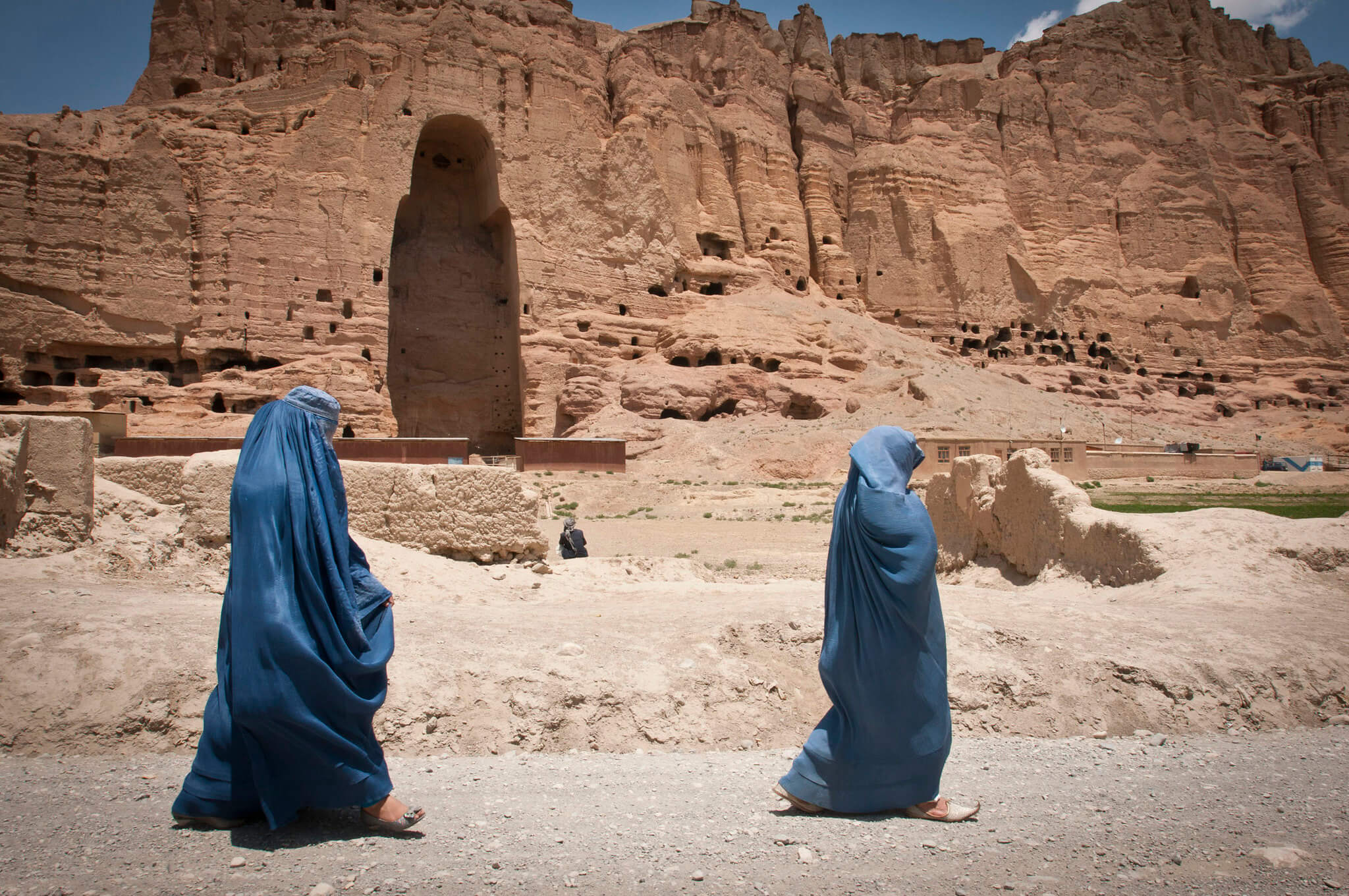 Ansaray - Two women walk past the huge cavity where one of the ancient Buddhas of Bamiyan, known to locals as the Father Buddha, used to stand, 2012. DVIDSHUB-Flickr.