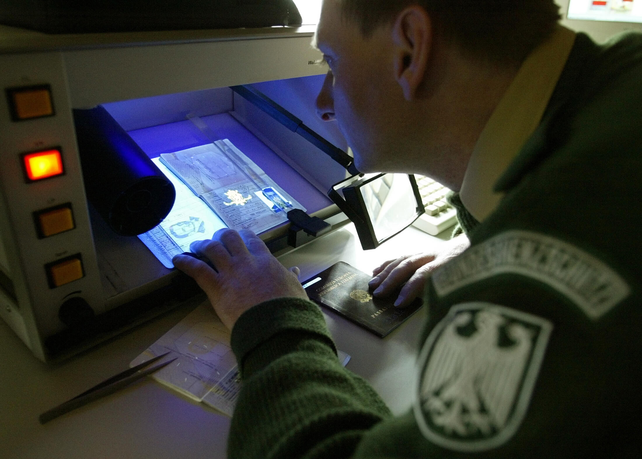 Een Duitse douanebeambte controleert een paspoort in 2004. Reuters