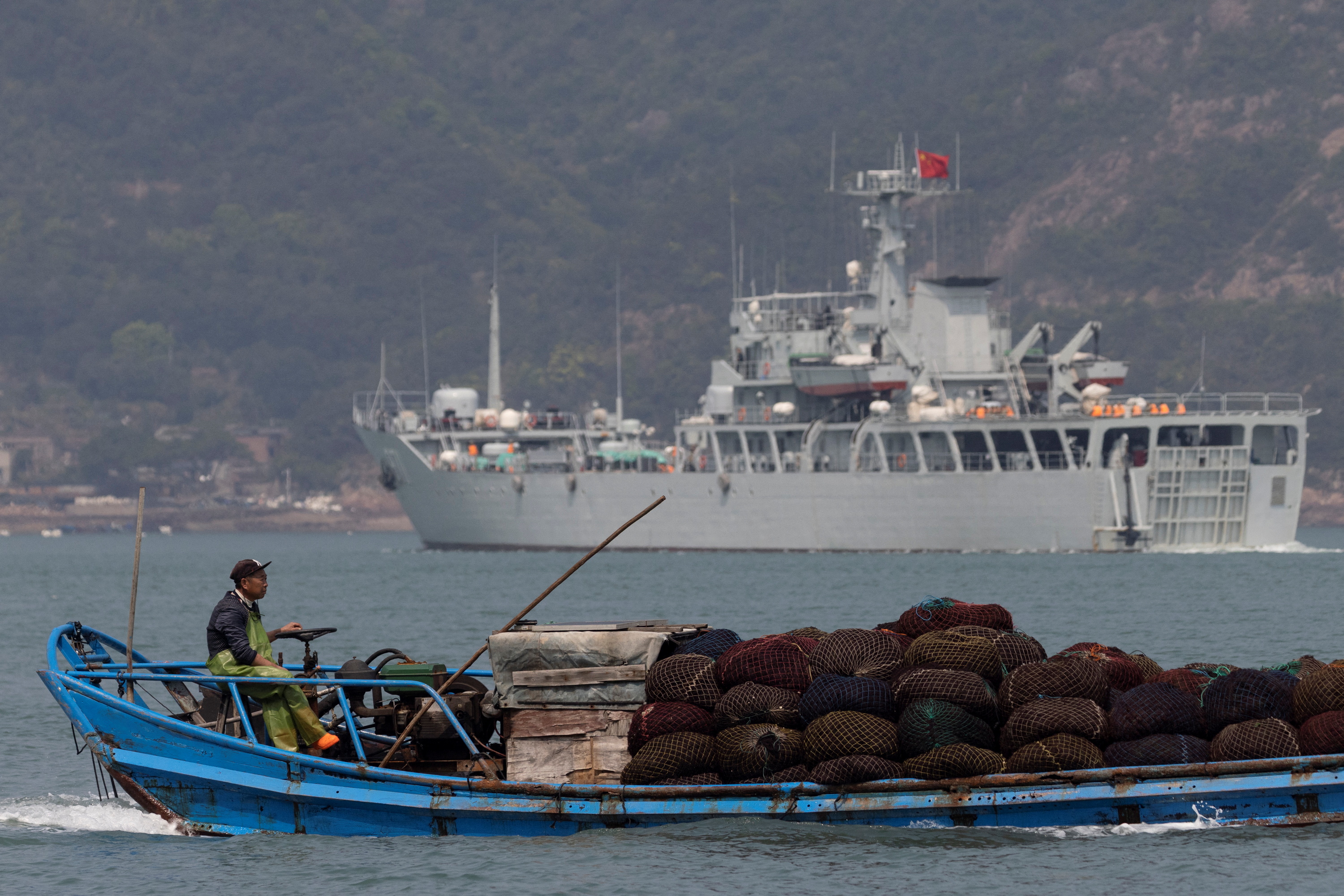 Martin - A fishing boat sails past a Chinese warship during a military drill off the Chinese coast near Fuzhou, Fujian Province, across from the Taiwan-controlled Matsu Islands, China, April 11, 2023.