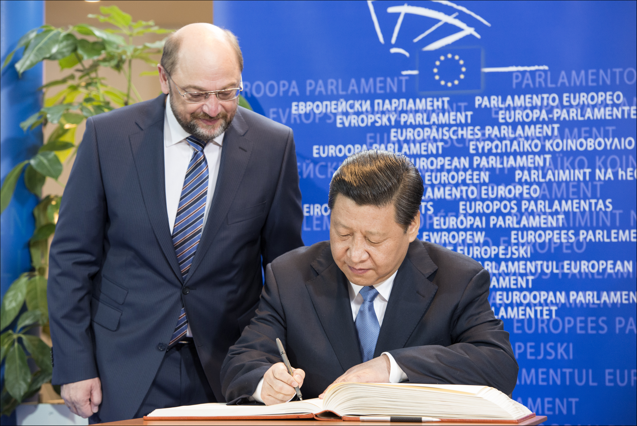 Schulz watches over the shoulder of Xi Jinping as he signs a document. Source: Flickr / European Parliament