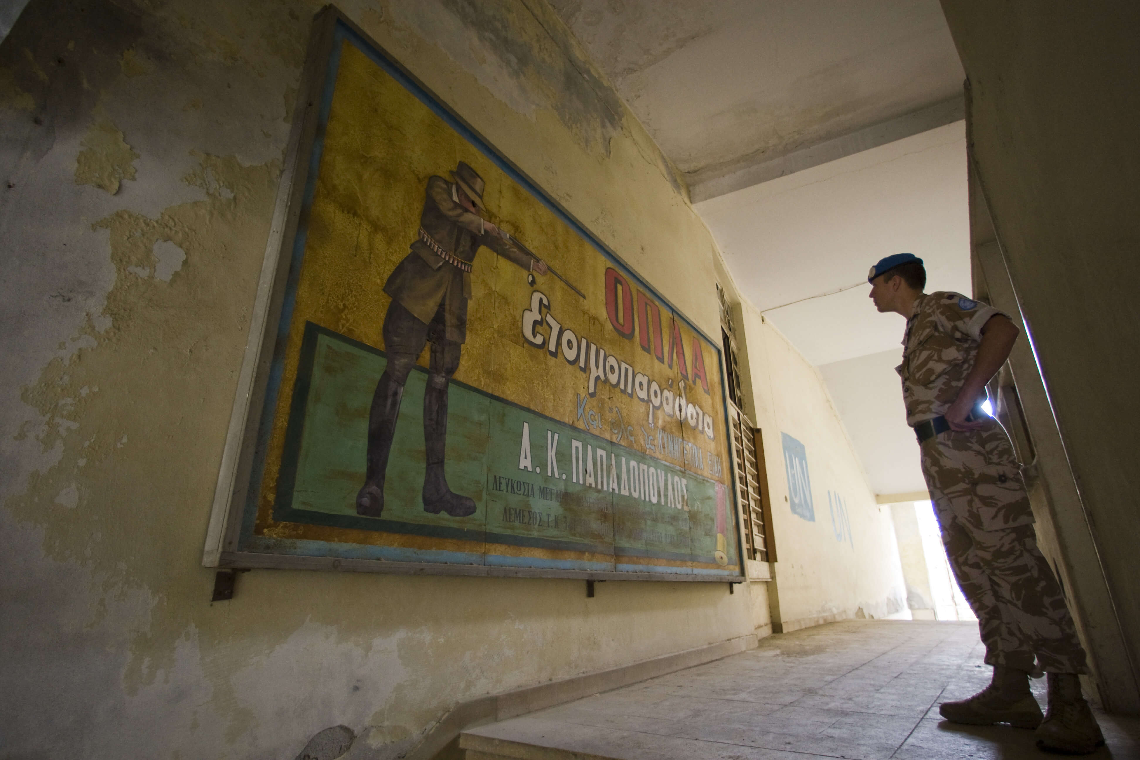 Een VN soldaat bestudeert een oude poster in de verlaten buffer zone tussen Turks- en Grieks-Cyprus. © United Nations Photo/Flickr